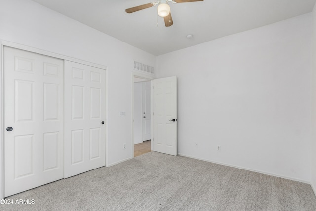 unfurnished bedroom featuring ceiling fan, light colored carpet, and a closet