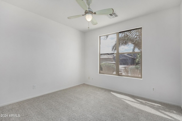 carpeted empty room with a ceiling fan, visible vents, and baseboards