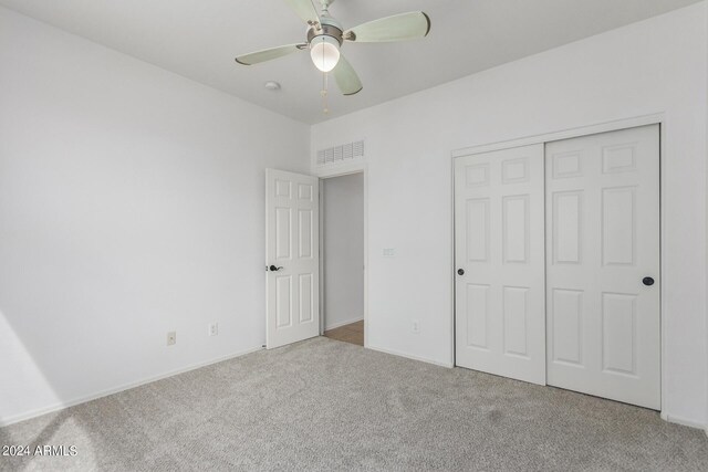 unfurnished bedroom featuring light colored carpet, ceiling fan, and a closet