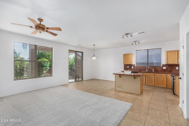 kitchen featuring tasteful backsplash, a kitchen island, a breakfast bar area, a sink, and light tile patterned flooring