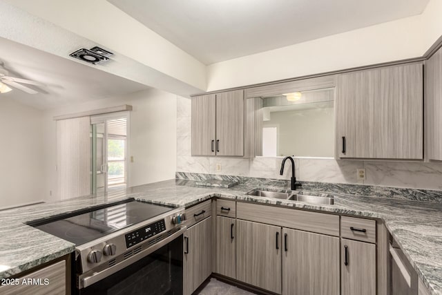 kitchen with stainless steel range with electric cooktop, a sink, a ceiling fan, decorative backsplash, and a peninsula