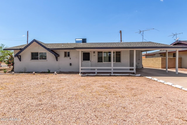 ranch-style home featuring a carport, a porch, roof with shingles, fence, and brick siding