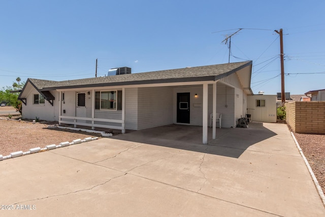 view of front of home featuring driveway, a carport, a shingled roof, and fence