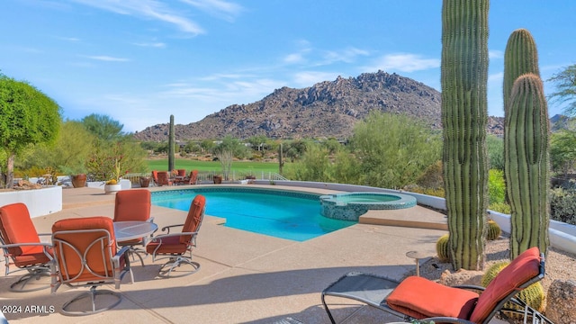 view of pool featuring a patio, a mountain view, and an in ground hot tub