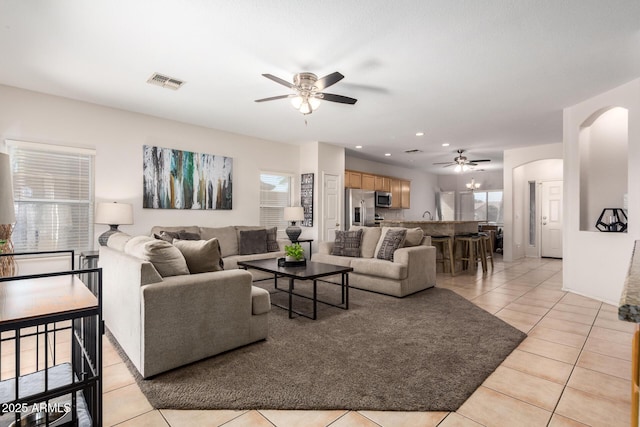 living area with arched walkways, light tile patterned floors, recessed lighting, visible vents, and a ceiling fan