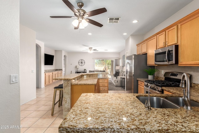 kitchen with visible vents, appliances with stainless steel finishes, open floor plan, a sink, and backsplash