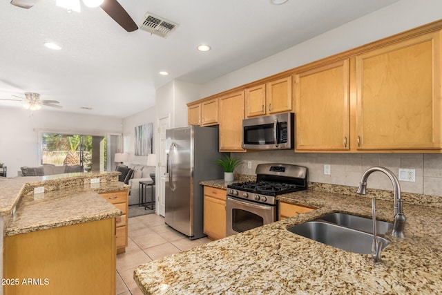 kitchen with stainless steel appliances, visible vents, a ceiling fan, open floor plan, and a sink