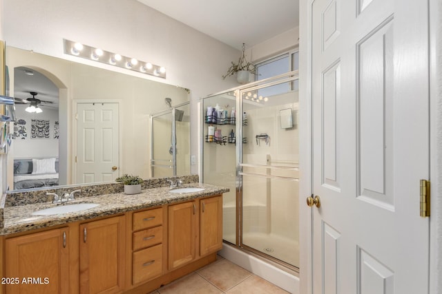 bathroom with a stall shower, a ceiling fan, ensuite bathroom, tile patterned flooring, and a sink