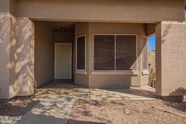 view of exterior entry featuring a patio and stucco siding