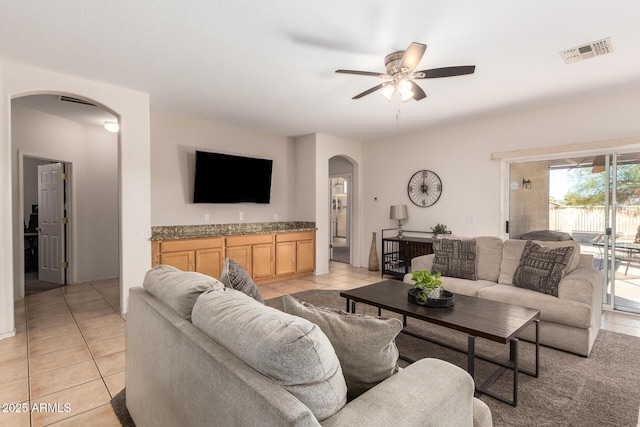 living area featuring arched walkways, visible vents, ceiling fan, and light tile patterned floors