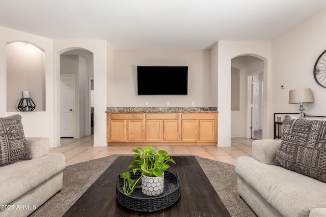 living area featuring arched walkways and light tile patterned floors