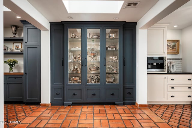 bar featuring white cabinets, a skylight, and oven