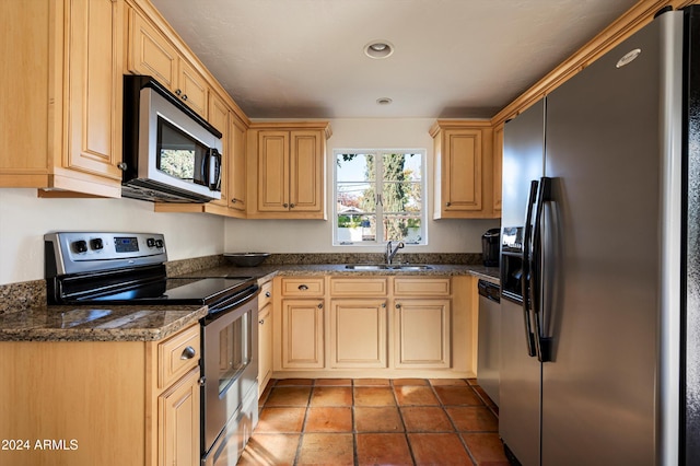 kitchen featuring dark tile patterned flooring, sink, appliances with stainless steel finishes, light brown cabinets, and dark stone counters