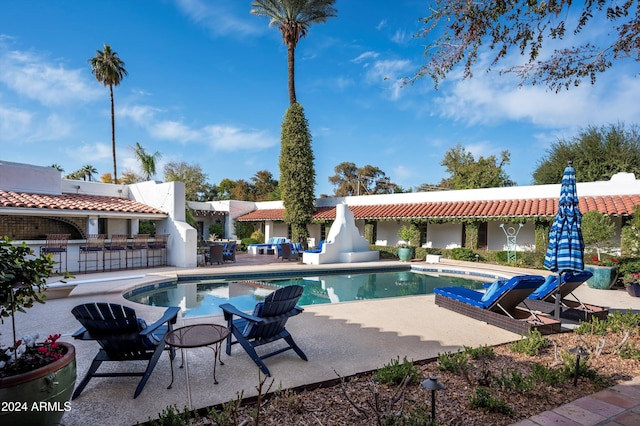 view of pool featuring exterior bar and a patio