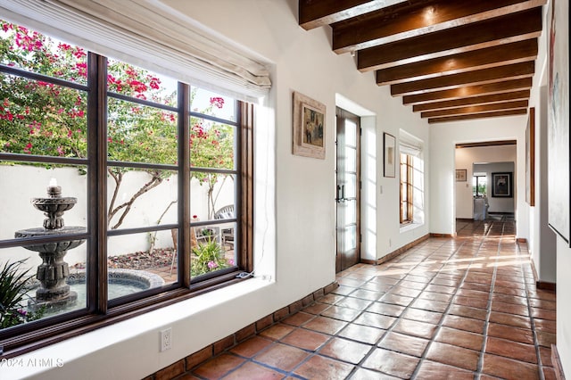 hall with beamed ceiling and tile patterned flooring