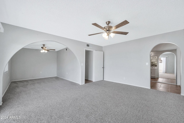 carpeted spare room with ceiling fan and a textured ceiling