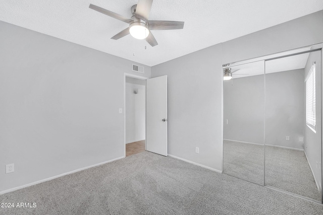 unfurnished bedroom featuring light carpet, a closet, and ceiling fan