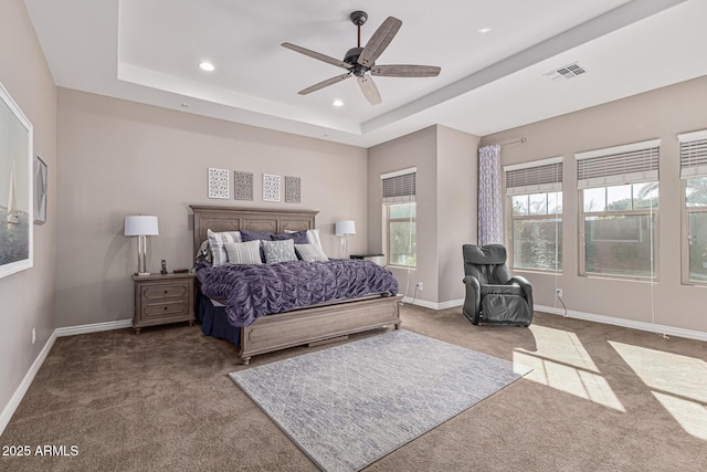 carpeted bedroom with a raised ceiling and ceiling fan