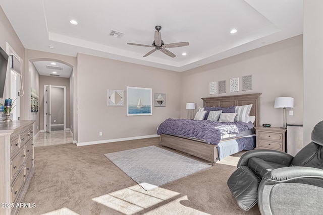 carpeted bedroom featuring ceiling fan and a tray ceiling