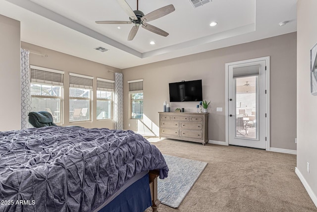 bedroom featuring multiple windows, light carpet, a raised ceiling, and ceiling fan