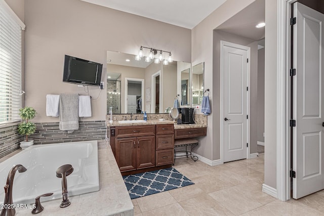 bathroom with tile patterned flooring, vanity, and tiled tub