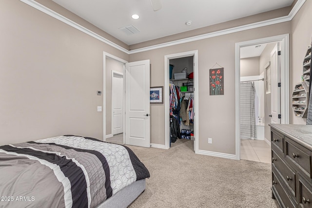 bedroom with a spacious closet, a closet, ensuite bathroom, and light carpet