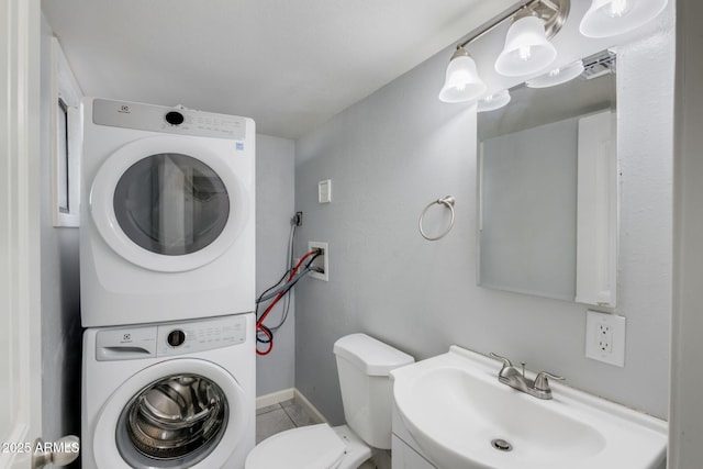 bathroom with a sink, toilet, visible vents, and stacked washing maching and dryer