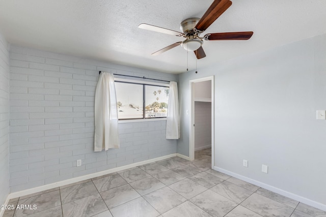 unfurnished room featuring baseboards, a textured ceiling, and a ceiling fan