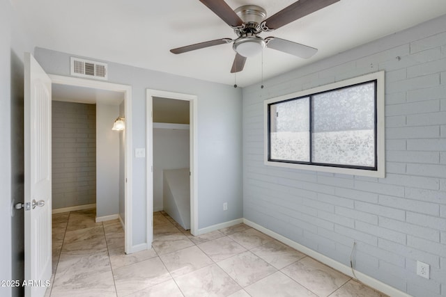 unfurnished bedroom featuring visible vents, baseboards, a closet, and brick wall