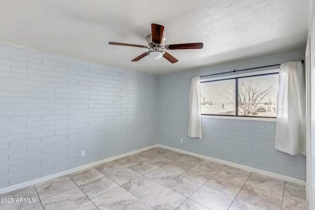 unfurnished room featuring a ceiling fan, baseboards, brick wall, and a textured ceiling