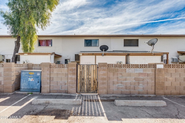 view of property featuring a fenced front yard, uncovered parking, and a gate