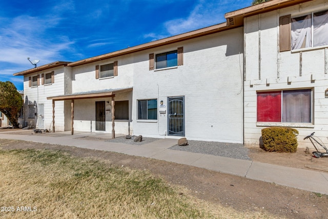 townhome / multi-family property featuring a front yard and stucco siding