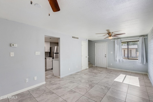 unfurnished living room with visible vents, baseboards, a textured ceiling, and ceiling fan