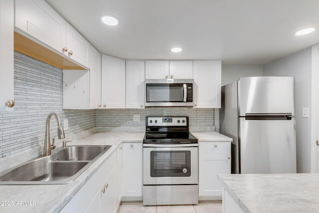 kitchen with a sink, stainless steel appliances, light countertops, white cabinetry, and tasteful backsplash