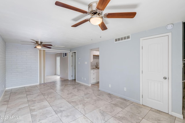 interior space with visible vents, ensuite bathroom, a sink, brick wall, and baseboards