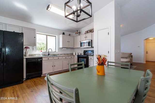 kitchen with hardwood / wood-style floors, a chandelier, black appliances, sink, and vaulted ceiling