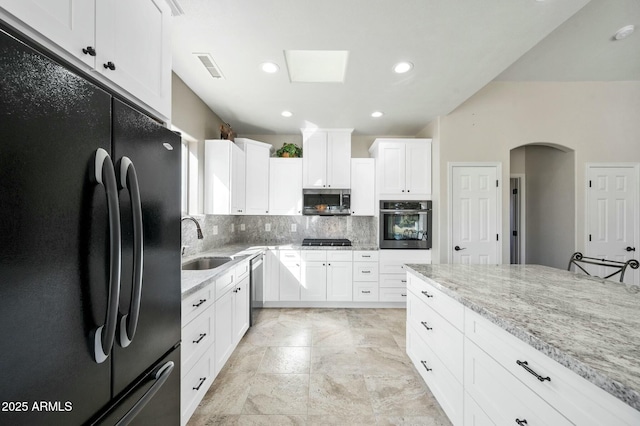 kitchen featuring light stone countertops, appliances with stainless steel finishes, white cabinetry, and sink