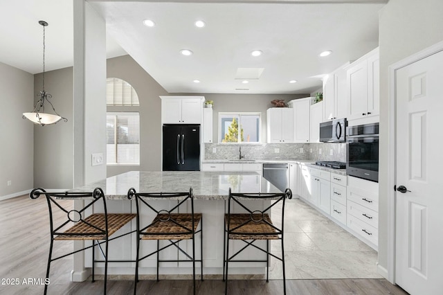 kitchen featuring decorative backsplash, appliances with stainless steel finishes, a kitchen island, sink, and white cabinetry