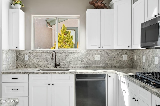 kitchen with white cabinets, black gas stovetop, sink, light stone countertops, and tasteful backsplash