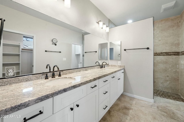 bathroom featuring tiled shower and vanity