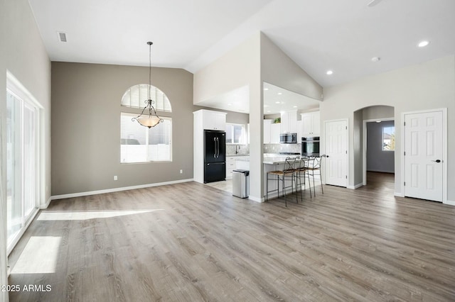 kitchen with a kitchen breakfast bar, stainless steel appliances, a center island, white cabinetry, and hanging light fixtures