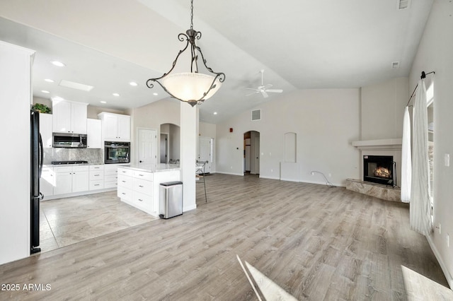 kitchen with white cabinetry, tasteful backsplash, pendant lighting, lofted ceiling, and appliances with stainless steel finishes