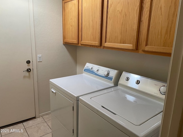 laundry room with washer and dryer, light tile patterned flooring, and cabinets