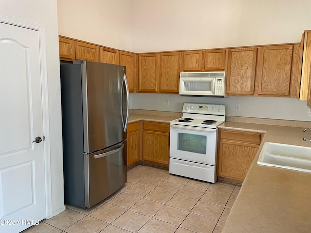 kitchen featuring light tile patterned flooring, a high ceiling, white appliances, and sink