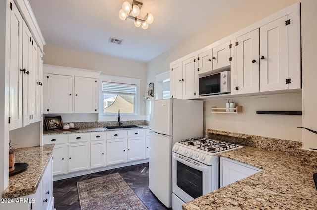 kitchen with white appliances, a sink, white cabinets, and light stone counters