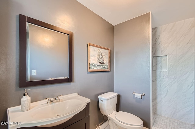 full bathroom featuring toilet, tiled shower, and vanity
