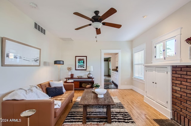 living area with a ceiling fan, light wood-type flooring, and baseboards