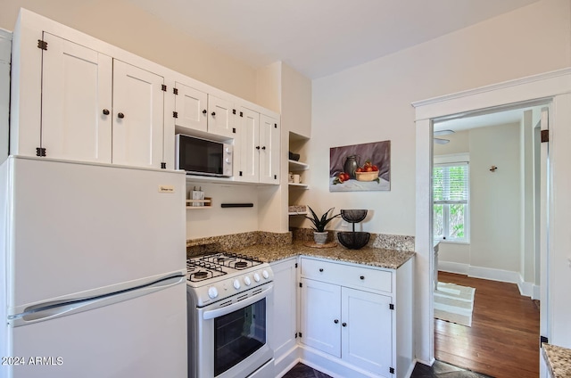 kitchen with white appliances, dark wood-style flooring, white cabinetry, and light stone countertops