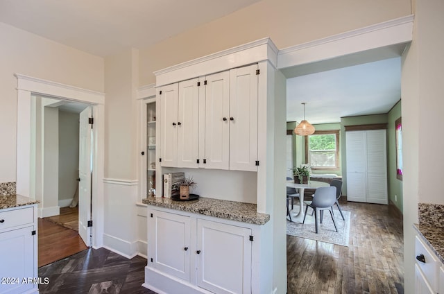 kitchen with white cabinets, light stone counters, and dark wood finished floors