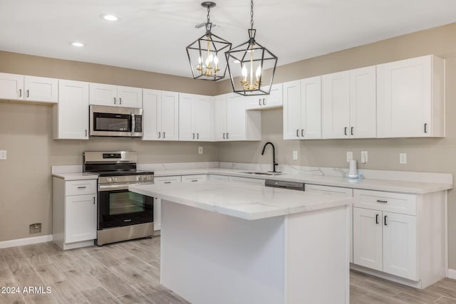 kitchen featuring white cabinets, stainless steel appliances, a center island, and light hardwood / wood-style flooring